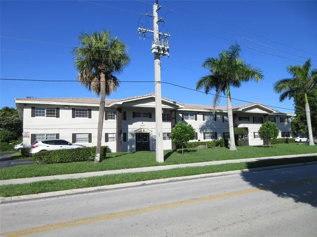 a front view of a house with a yard and palm trees