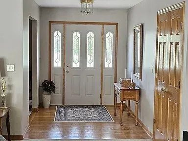 a view of a hallway with wooden floor and a livingroom with furniture