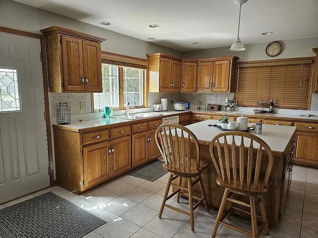 a kitchen with a cabinets a sink and chairs in it