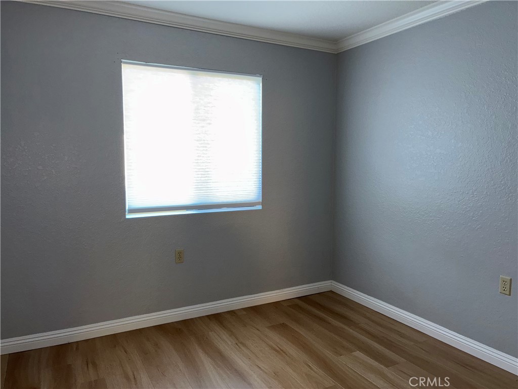 10151 Arrow Route, Unit 11 Rancho Cucamonga, CA 91730 - Photo 13 of 28 a view of an empty room with wooden floor and a window