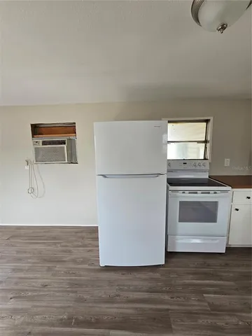 a view of kitchen and empty room with wooden floor