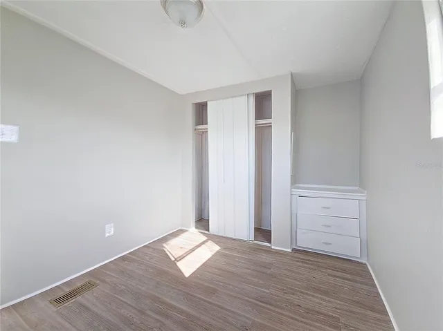 an empty room with wooden floor and closet
