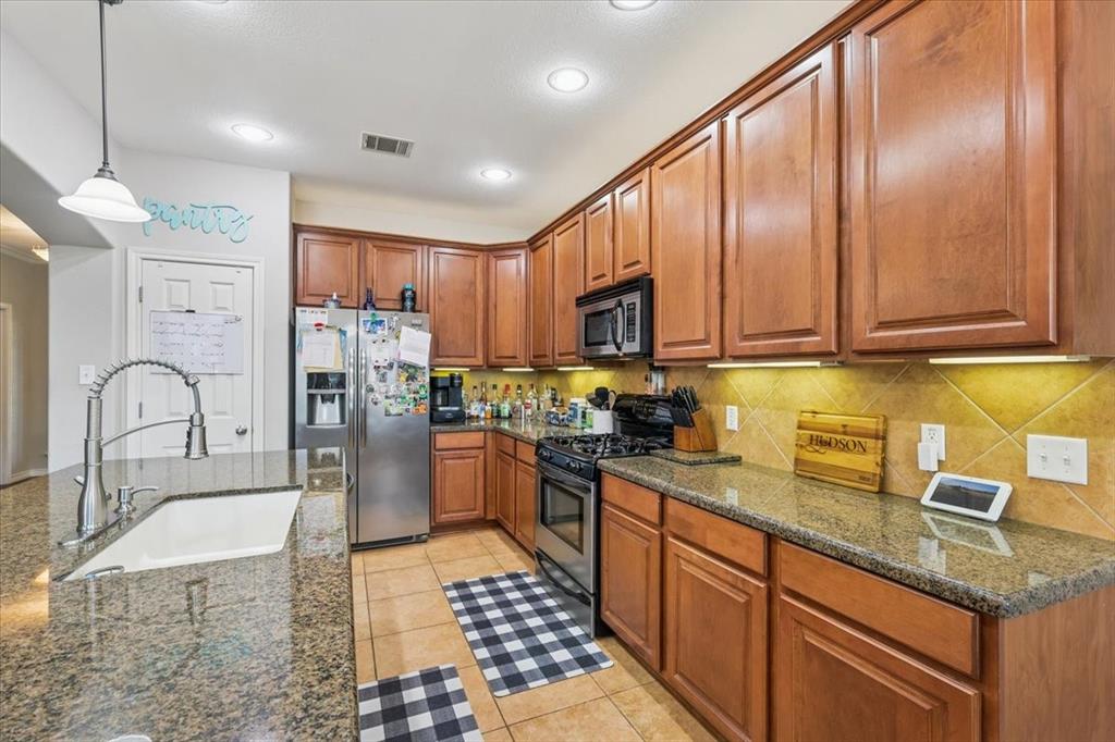 868 Valley Ridge Road Burleson, TX 76028 - Photo 12 of 40 a kitchen with stainless steel appliances granite countertop a refrigerator a sink a stove top oven and a dining table