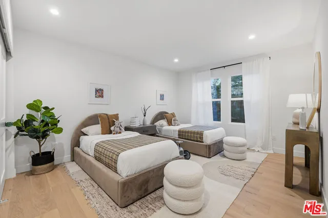 a spacious bedroom with two beds and a potted plant