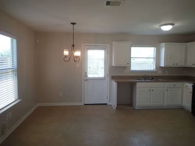 a kitchen with stainless steel appliances granite countertop white cabinets and window