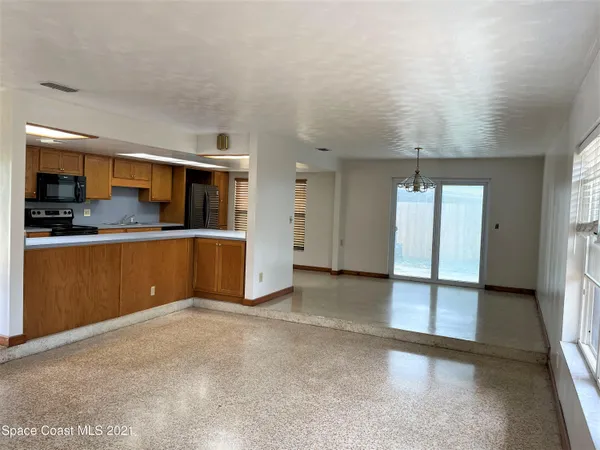 an empty room with kitchen view and a window