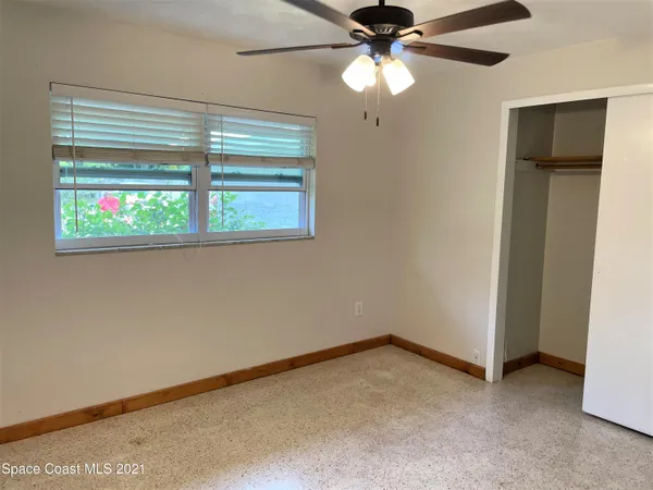 an empty room with windows and fan