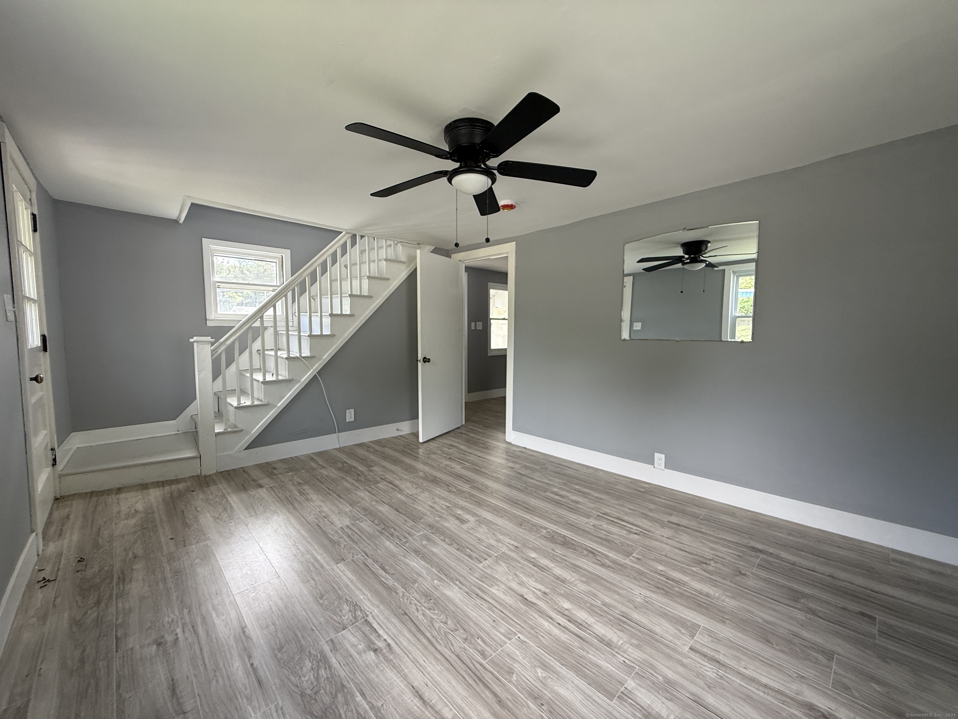 1402 Waterbury Road Thomaston, CT 06787 - Photo 4 of 13 a view of an empty room with wooden floor and a ceiling fan