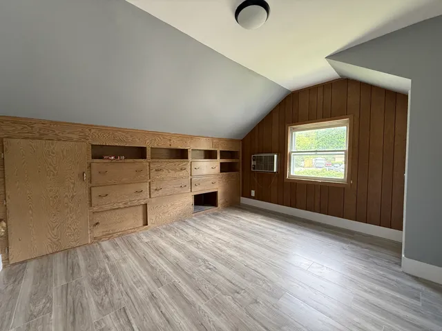 an empty room with wooden floor closet and windows