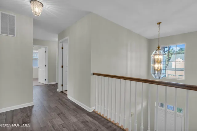 a view of a hallway with wooden floor and chandelier