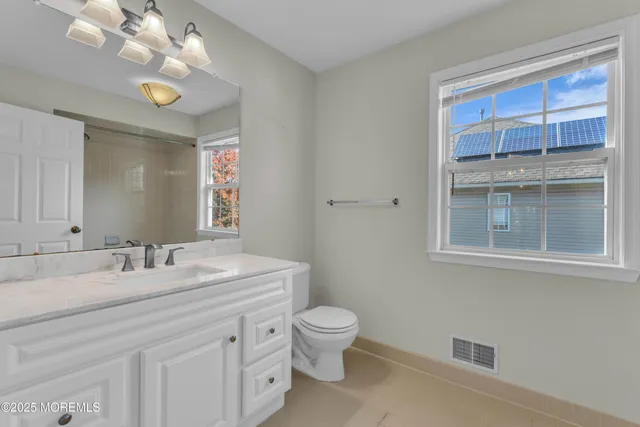 a bathroom with a granite countertop toilet sink and mirror