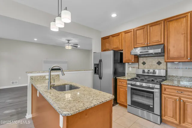 a kitchen with stainless steel appliances granite countertop a sink dishwasher a stove a refrigerator with a dining table and chairs