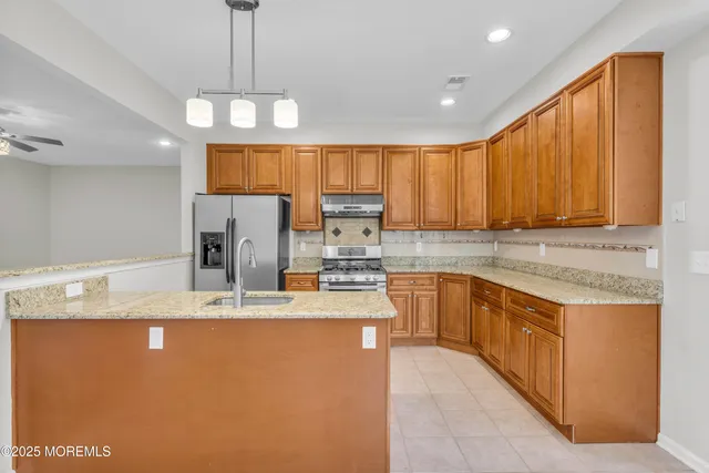 a kitchen with stainless steel appliances granite countertop a sink refrigerator and cabinets