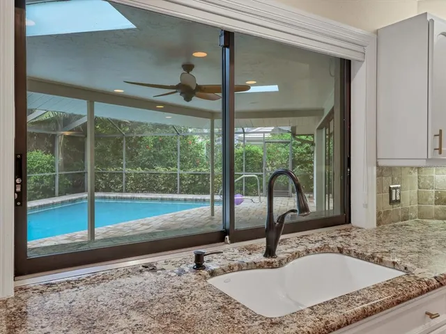 a bathroom with a granite countertop sink and a large window