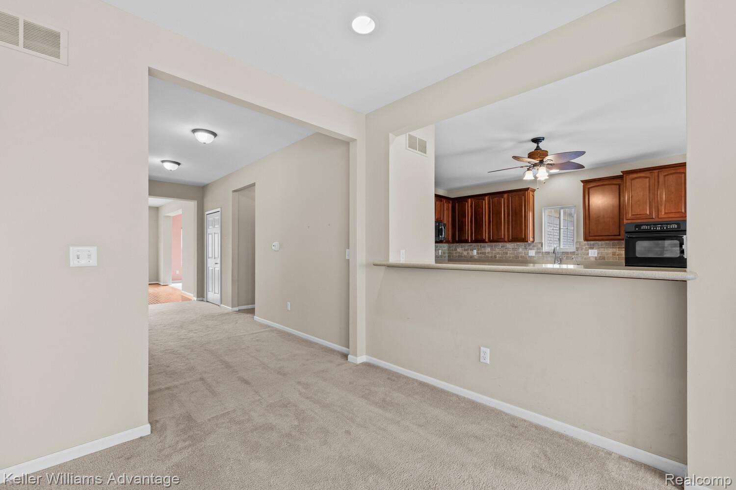 4100 Norwich Court Rochester, MI 48306 - Photo 13 of 72 Kitchen featuring tasteful backsplash, black oven, light countertops, light carpet, and ceiling fan