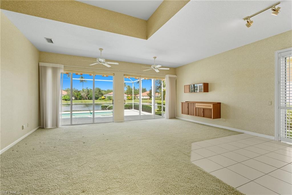 5925 Bermuda Lane Naples, FL 34119 - Photo 5 of 24 Unfurnished living room with light carpet, rail lighting, light tile patterned floors, and a water view