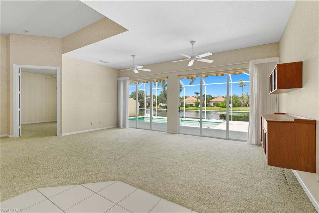 5925 Bermuda Lane Naples, FL 34119 - Photo 7 of 24 Unfurnished living room with light colored carpet, light tile patterned floors, a sunroom, a water view, and a residential view