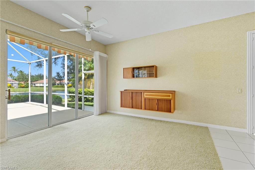 5925 Bermuda Lane Naples, FL 34119 - Photo 8 of 24 Unfurnished living room featuring a water view, a sunroom, light carpet, a ceiling fan, and light tile patterned floors