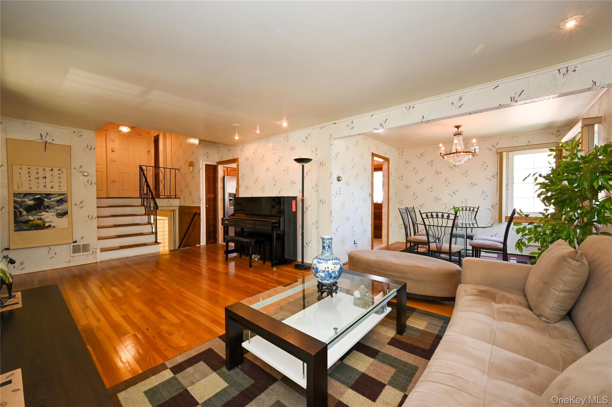 28-30 210th Street Queens, NY 11360 - Photo 2 of 19 Living room featuring wallpapered walls, wood finished floors, stairs, and a chandelier