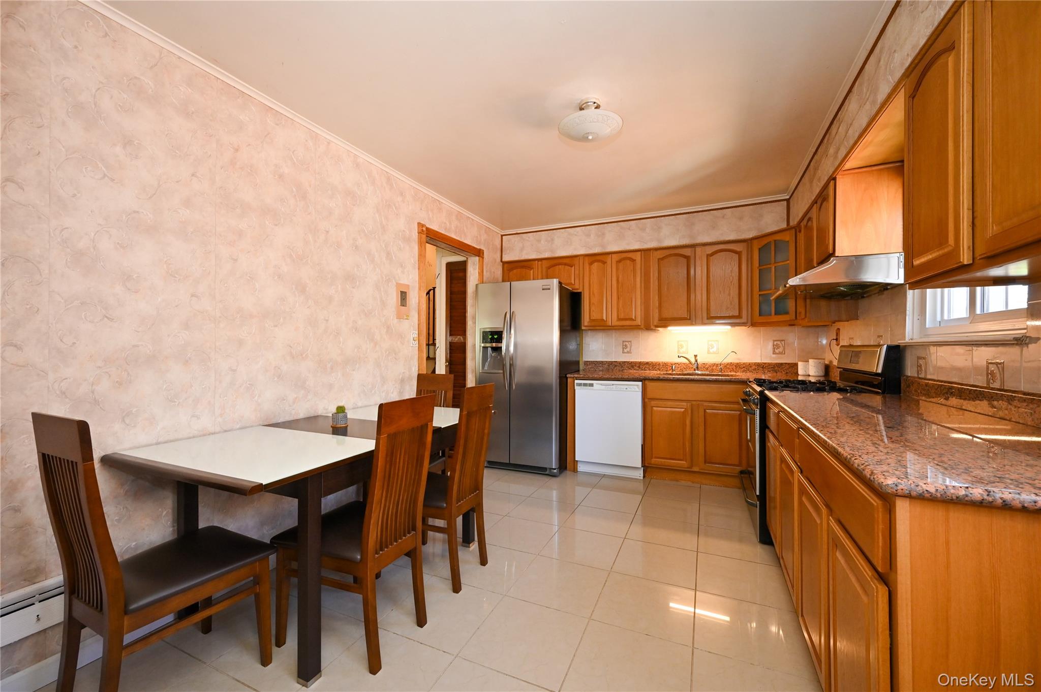 28-30 210th Street Queens, NY 11360 - Photo 6 of 19 Kitchen with range with gas cooktop, brown cabinets, glass insert cabinets, stainless steel refrigerator with ice dispenser, and crown molding