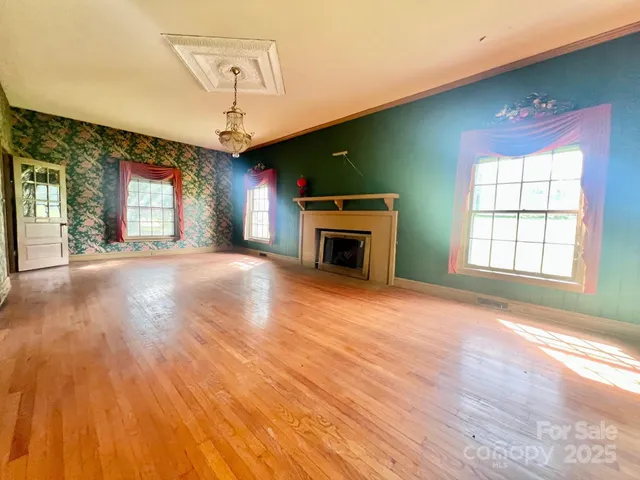 an empty room with windows fireplace and a wooden floor