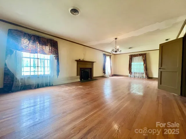 an empty room with wooden floor a fireplace and windows