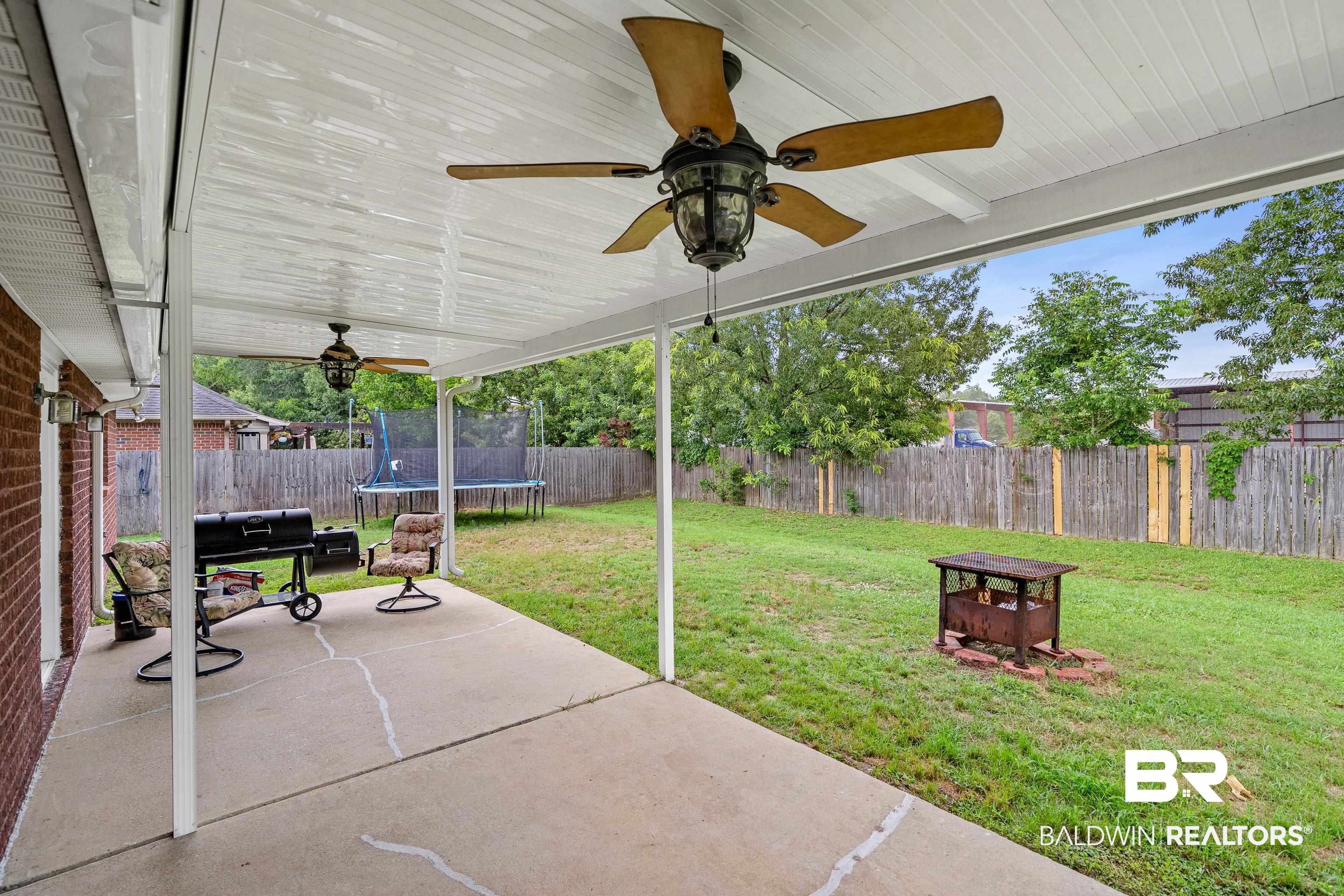 9552 Collier Loop Daphne, AL 36526 - Photo 23 of 28 View of patio / terrace with a trampoline, a ceiling fan, and a fire pit