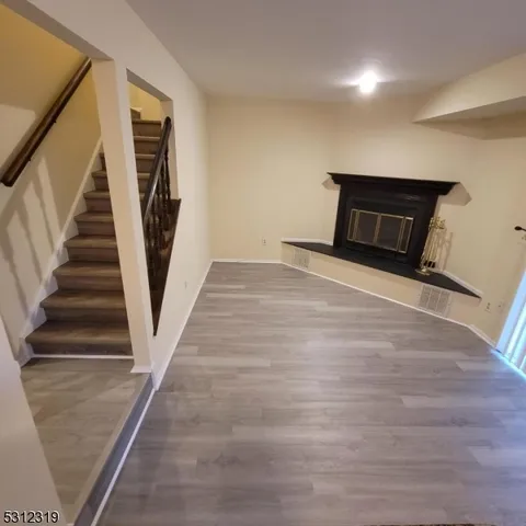 a view of an empty room with wooden floor and a fireplace