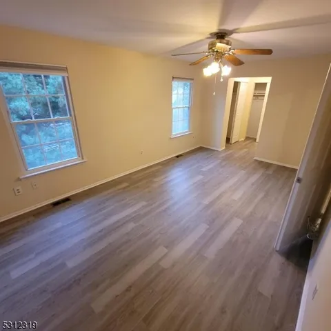 a view of an empty room with a window and wooden floor