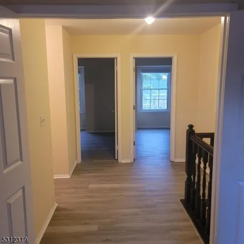 a view of a hallway with wooden floor and stairs