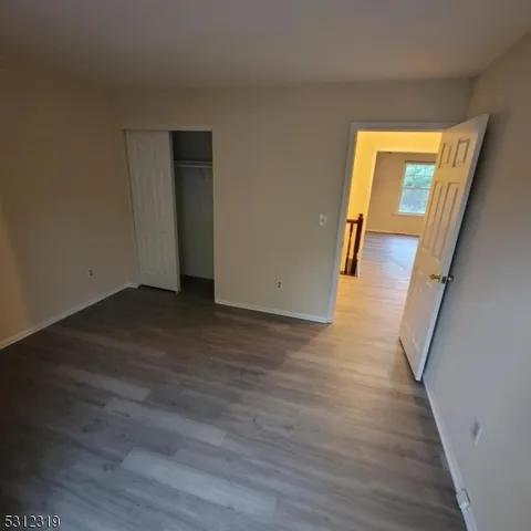 a view of a hallway with wooden floor and closet