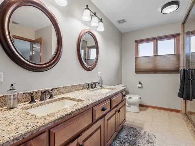 a bathroom with a granite countertop double vanity sink and a mirror