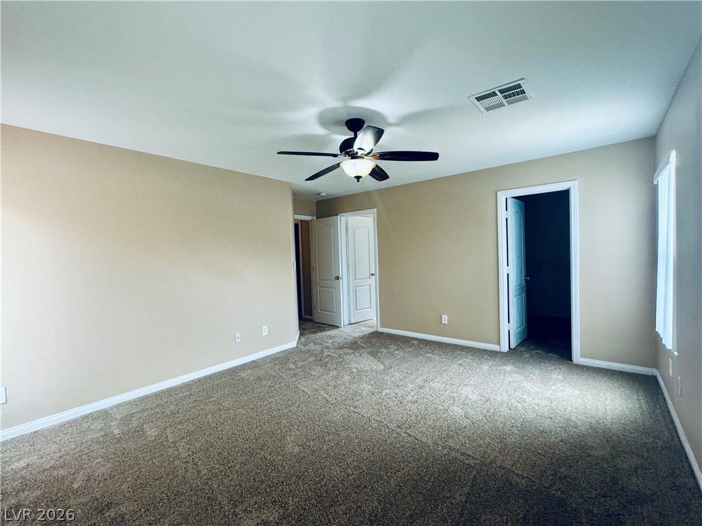 8617 Palomino Ranch Street Las Vegas, NV 89131 - Photo 21 of 27 A spacious chamber awaits, offering plush carpeting and a convenient ceiling fan for ultimate comfort.
