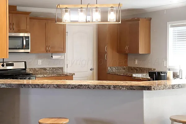a large kitchen with granite countertop a sink counter space and stainless steel appliances
