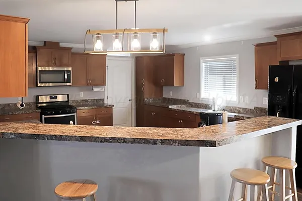 a kitchen with granite countertop a refrigerator stove and microwave