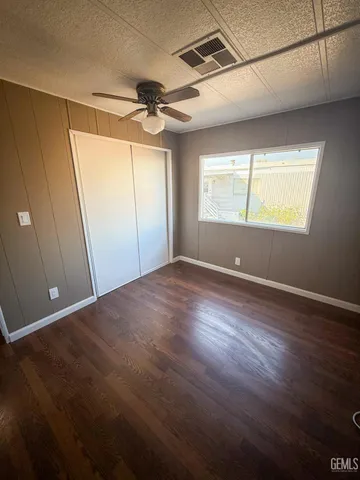 a view of empty room with wooden floor and fan