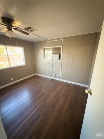 a view of empty room with wooden floor and fan