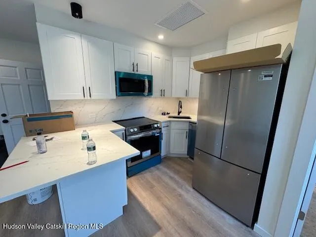 a kitchen with stainless steel appliances a refrigerator a sink a stove a microwave and island