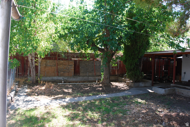 116 North 3rd Street Tooele, UT 84074 - Photo 35 of 45 Mature trees, concrete pathways, raised planter beds, a covered patio structure, and wood fencing define this outdoor space