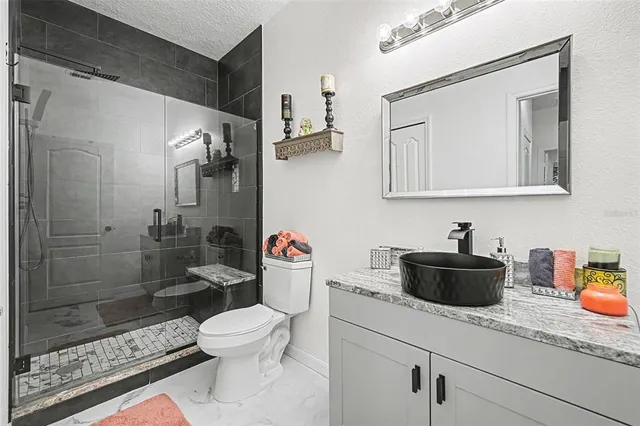 a bathroom with a granite countertop toilet a sink and a shower