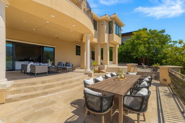 a view of a patio with couches table and chairs with wooden floor and fence