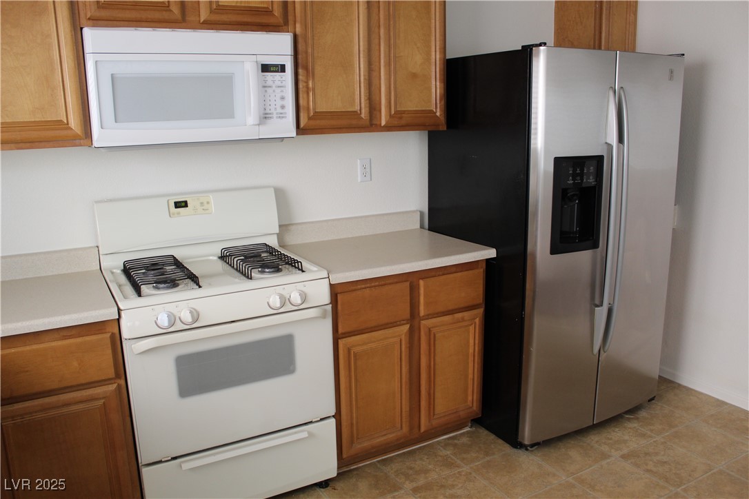 Undisclosed Address Las Vegas, NV 89129 - Photo 5 of 26 Kitchen featuring brown cabinets, white appliances