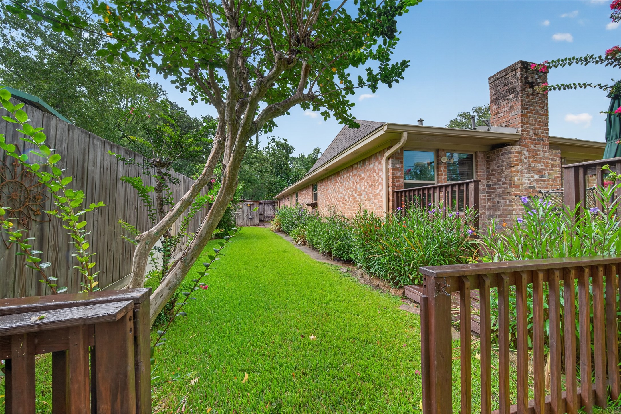 24719 Wilderness Road Spring, TX 77380 - Photo 36 of 42 Charming side yard with lush green grass, vibrant landscaping, and a wooden fence. The brick exterior adds to the home's inviting appeal. Ideal for outdoor enjoyment.