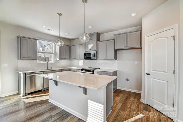 a kitchen with stainless steel appliances granite countertop a sink a stove a refrigerator and island with wooden floor