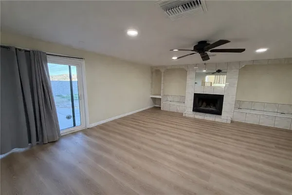 an empty room with wooden floor and a ceiling fan