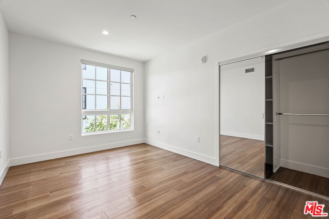 11847 Kiowa Avenue, Unit PH6 Los Angeles, CA 90049 - Photo 15 of 18 an empty room with wooden floor and windows