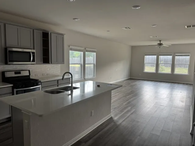 a kitchen with stainless steel appliances granite countertop a sink a stove and a wooden floors