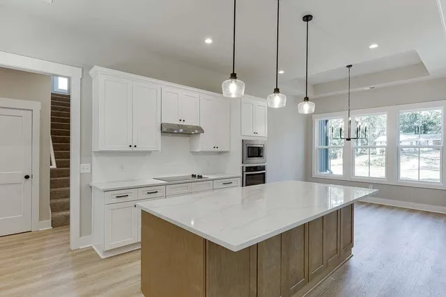 a kitchen with a stove a sink a wooden floor and a large window