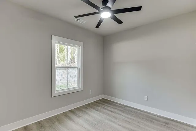 an empty room with a window and a fan