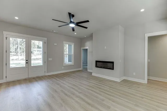 an empty room with wooden floor a ceiling fan and windows